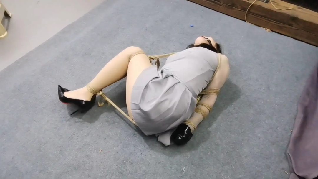 李然被直臂紧缚倒在地上，膝盖和脚踝紧缚让她无法逃脱，双手还被胶带缠绕，即使这样，她仍然奋力挣扎，只是徒劳无功罢了。-3